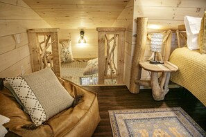 Une chambre confortable, aménagée dans le style d’un chalet, avec un lit, une chaise en bois, une petite table et un panier en osier.