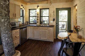A rustic cabin kitchen with wooden cabinets, a built-in oven, and a dining table with chairs.