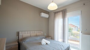 Ein Schlafzimmer mit Bett, Nachttischen, einer Klimaanlage, einem Fenster mit Vorhängen und Blick nach draußen.