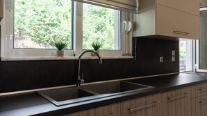 Eine moderne Küche mit schwarzem Arbeitsplatz, einer doppelten Spüle und einem Fenster mit Jalousien.