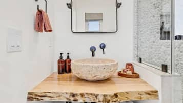 Un baño con lavamanos de piedra, un espejo y toallas.
