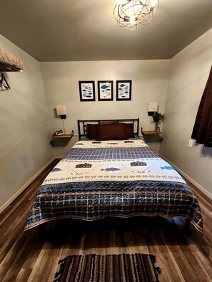 A bedroom with a bed, a nightstand, a lamp, and a wall-mounted shelf.