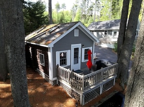 Eine kleine Holzhütte mit Veranda, umgeben von Bäumen.