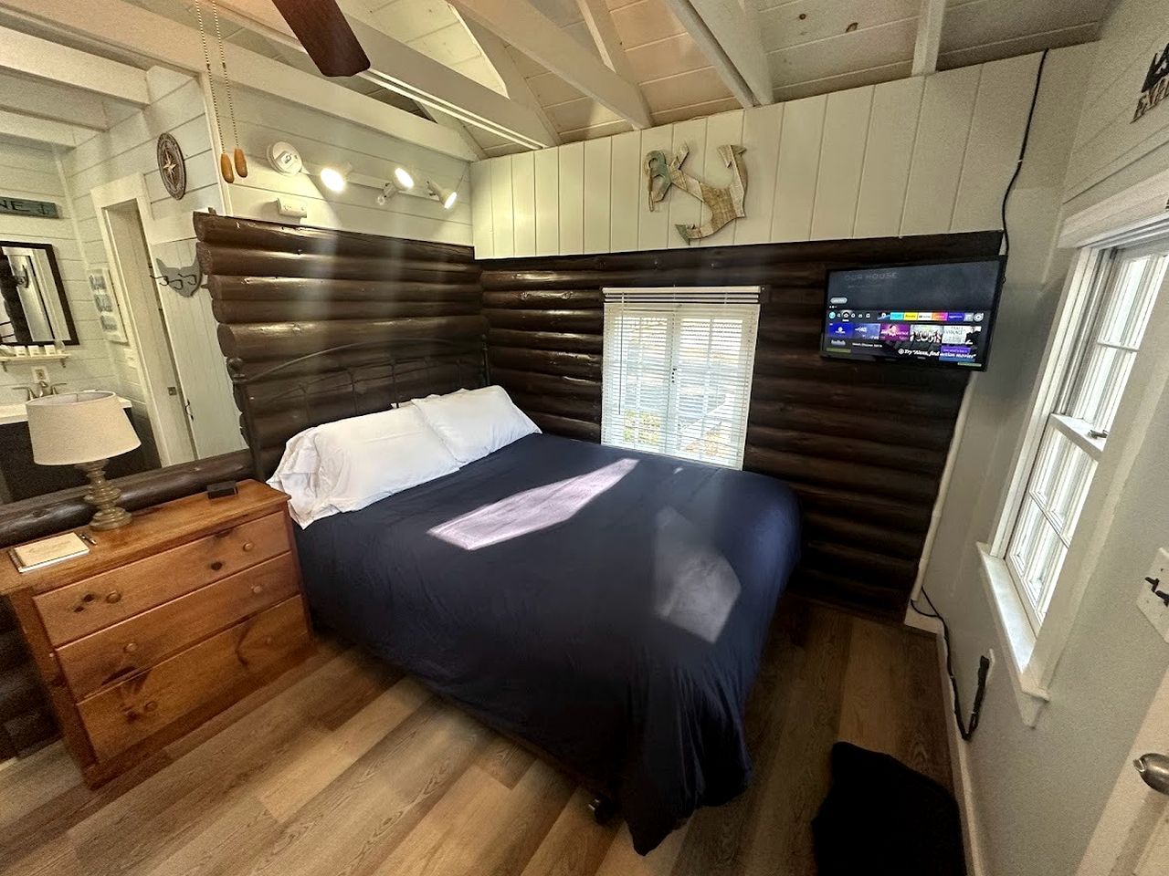 Ein Zimmer mit einem Bett, einem Holzschrank und einem an der Wand befestigten Fernseher.