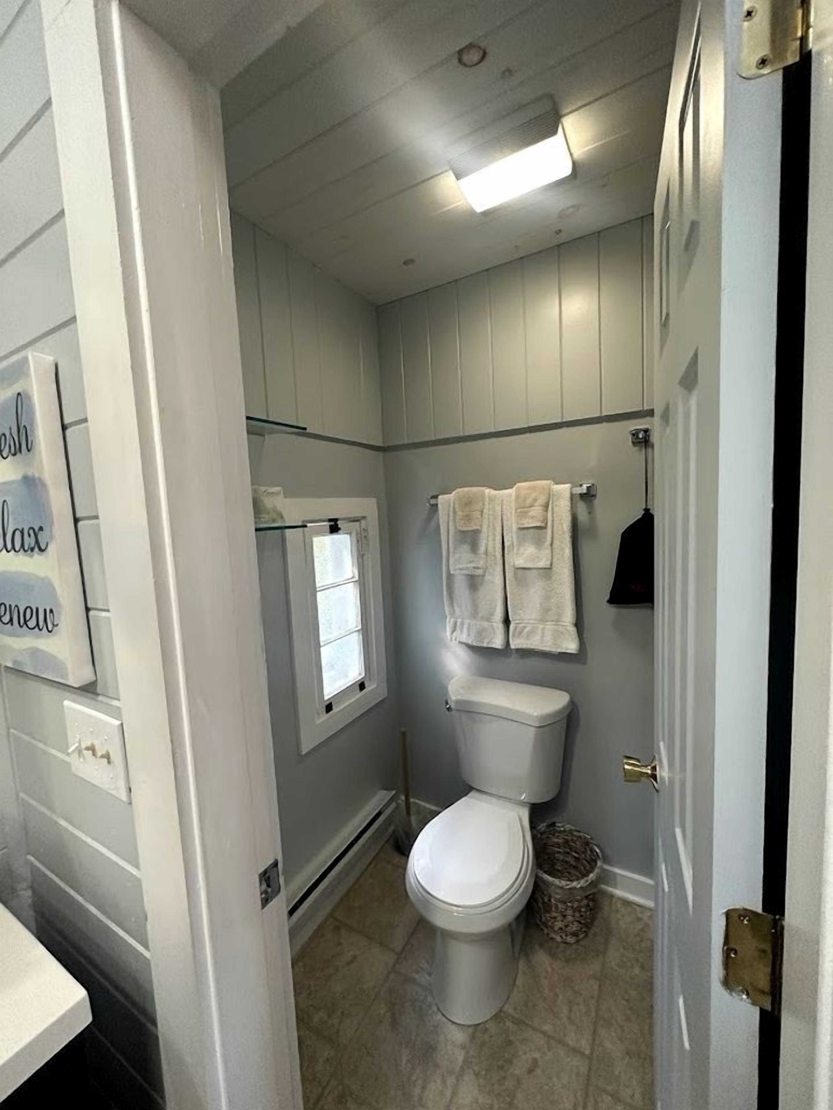 Un baño con inodoro, ventana y toallero.
