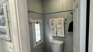 Un baño con inodoro, ventana y toallero.