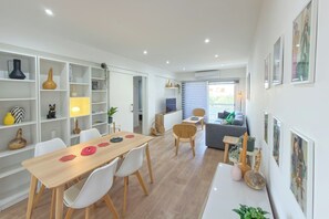 A modern interior with a dining area, white shelving, and artwork.