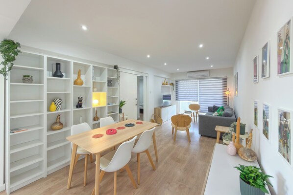 A modern living space with a dining area, white shelving units, and a cozy seating area.