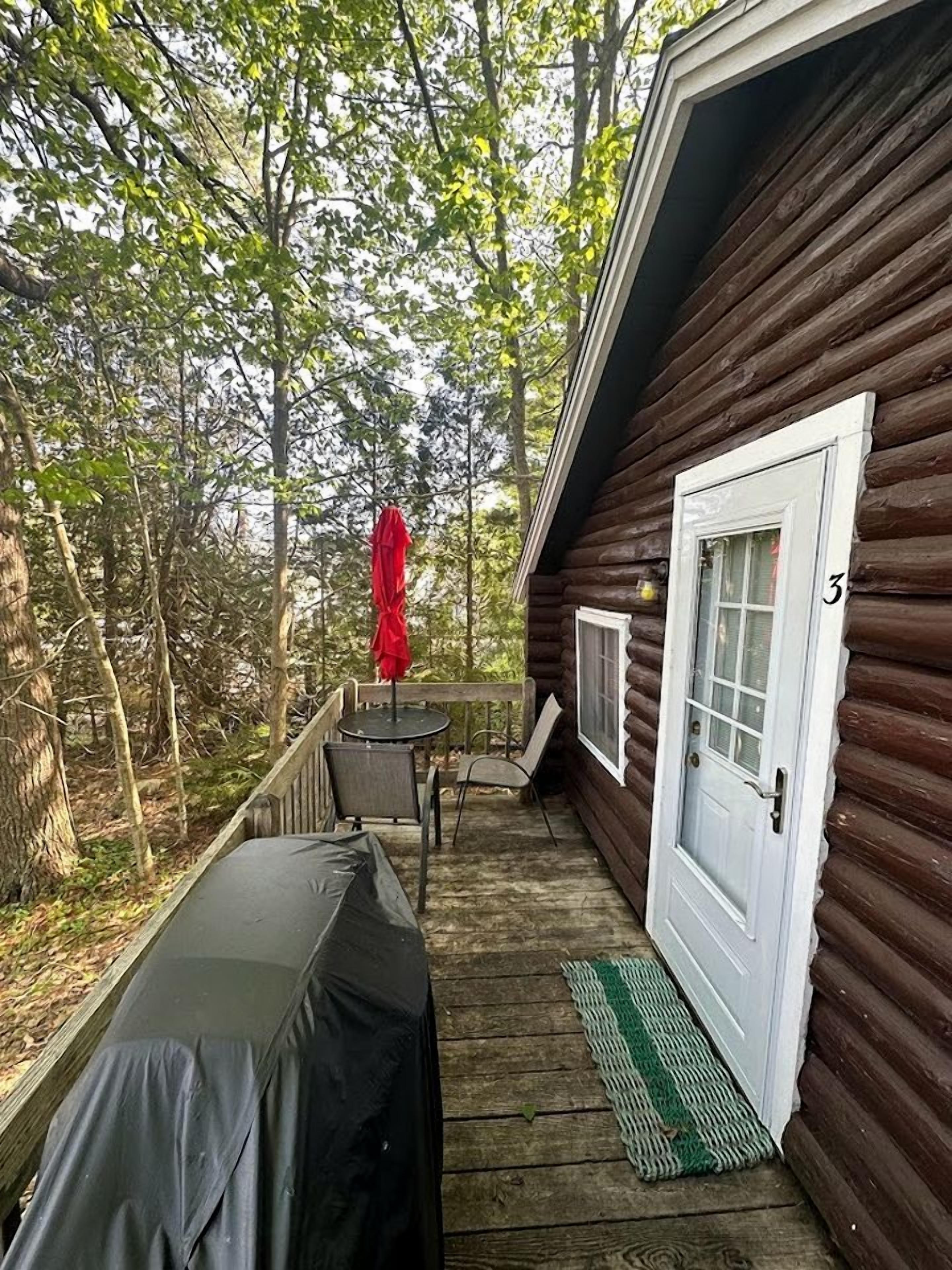 A wooden cabin with a porch, a covered table, and a door marked with the number 3.