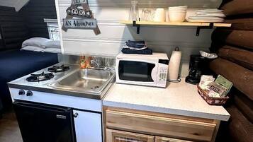 Une cuisine de taille réduite équipée d’une cuisinière à gaz, d’un évier, d’un four à micro-ondes et de meubles de rangement en bois.