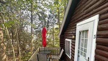 A wooden cabin with a porch, a covered table, and a door marked with the number 3.