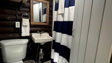 Un baño con inodoro, lavamanos y cortina de ducha.