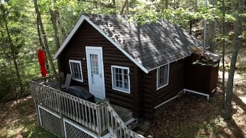 Une cabane en rondins avec un porche, une porte et un petit abri attenant.
