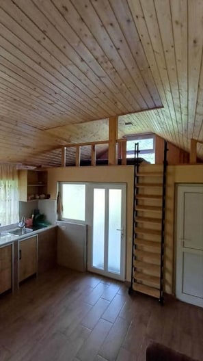 Eine Hütte mit Küchenzeile, einer Schiebetür und einem Schlafloft.