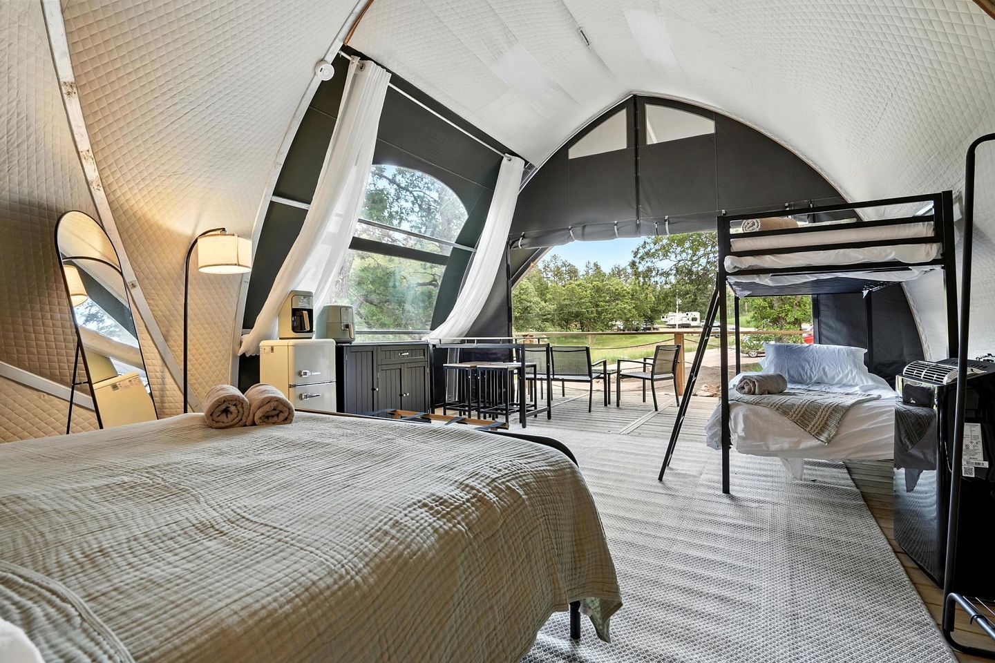 Un hébergement en tente comprenant un lit, une petite kitchenette et un coin salon avec vue sur l’extérieur.