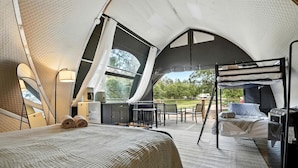 Un hébergement en tente comprenant un lit, une petite kitchenette et un coin salon avec vue sur l’extérieur.