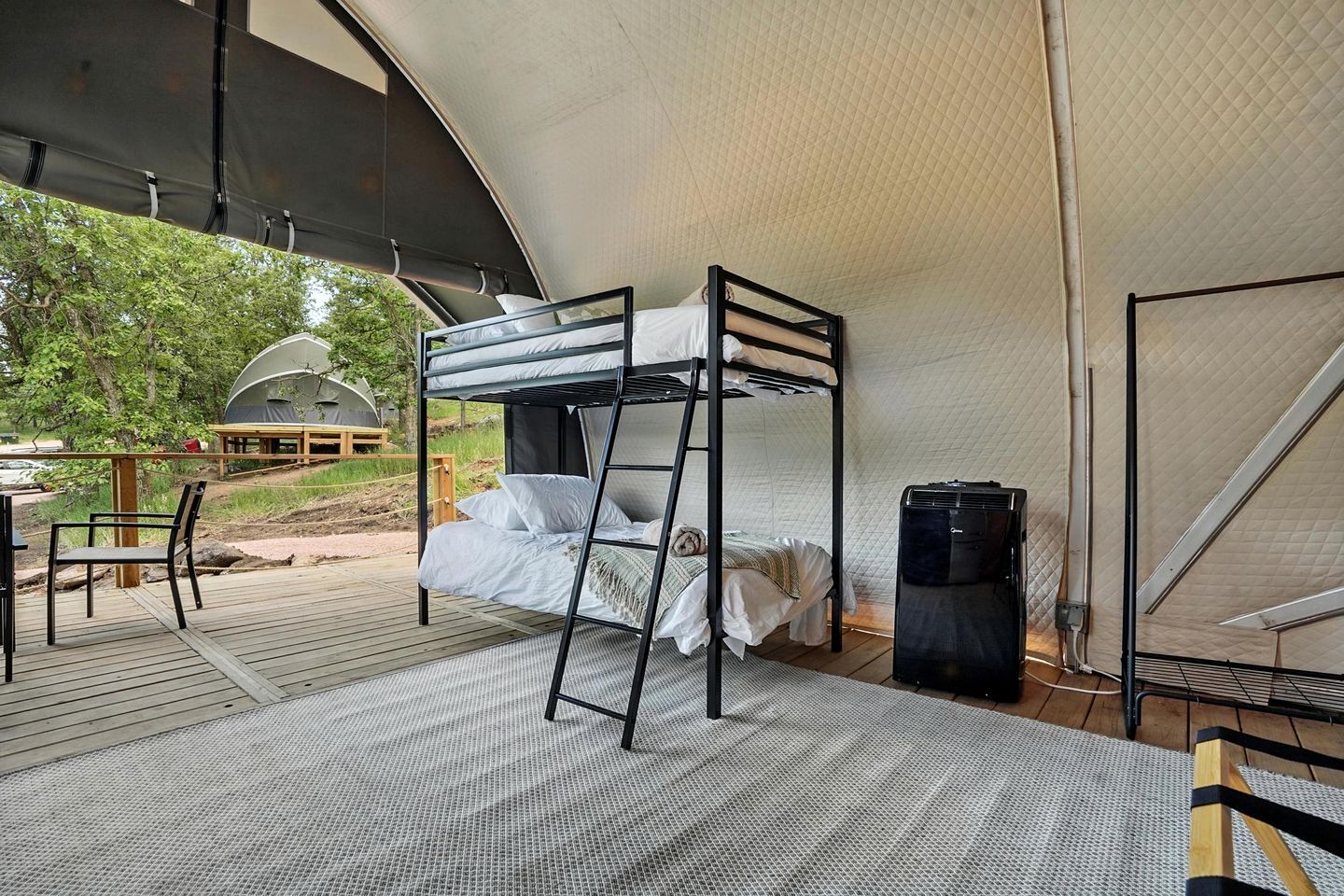 Un lit superposé dans un hébergement sous tente, avec vue sur l’extérieur.