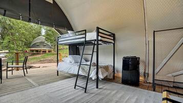 Un lit superposé dans un hébergement sous tente, avec vue sur l’extérieur.