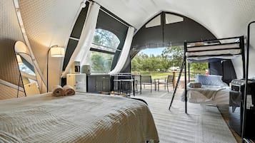 Un hébergement en tente comprenant un lit, une petite kitchenette et un coin salon avec vue sur l’extérieur.