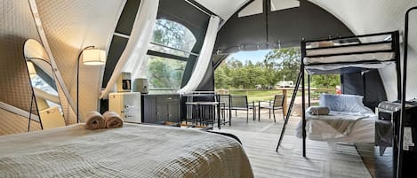 Un hébergement en tente comprenant un lit, une petite kitchenette et un coin salon avec vue sur l’extérieur.