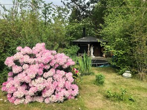 Un jardín con flores rosadas, un pabellón y una estatua.