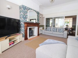 A living room with a fireplace, a television, a sofa, and a dining area visible through glass doors.