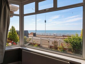A room with a view of the sea through a large window, a white railing outside, and a radiator below the window. - Sunrise Lodge (Bridlington)