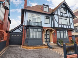 Una casa de dos pisos con un mirador, una puerta principal con un arco decorativo y un garaje.