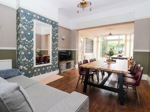A dining area with a wooden table and chairs, a television, and a patterned wallpaper. - Sunrise Lodge (Bridlington)