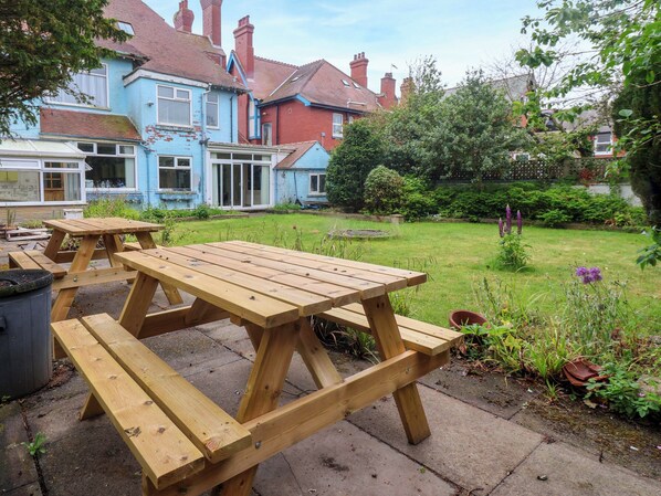 A wooden picnic table set in a garden with a house in the background. - Sunrise Lodge (Bridlington)