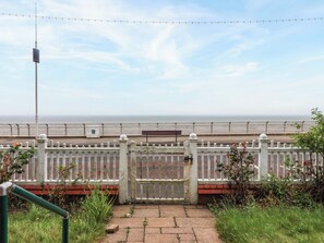 A coastal walkway with a white fence, a bench, and a clear view of the sea. - Sunrise Lodge (Bridlington)