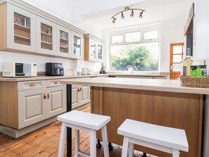 A kitchen with white cabinetry, a wooden island, and a large window with a view of greenery. - Sunrise Lodge (Bridlington)