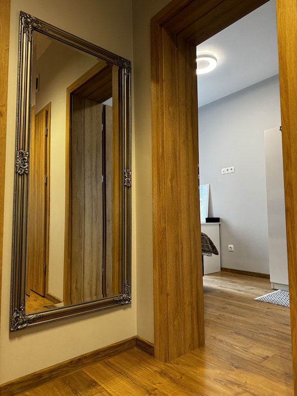 A hallway with a large ornate mirror, wooden door frames, and a ceiling light.