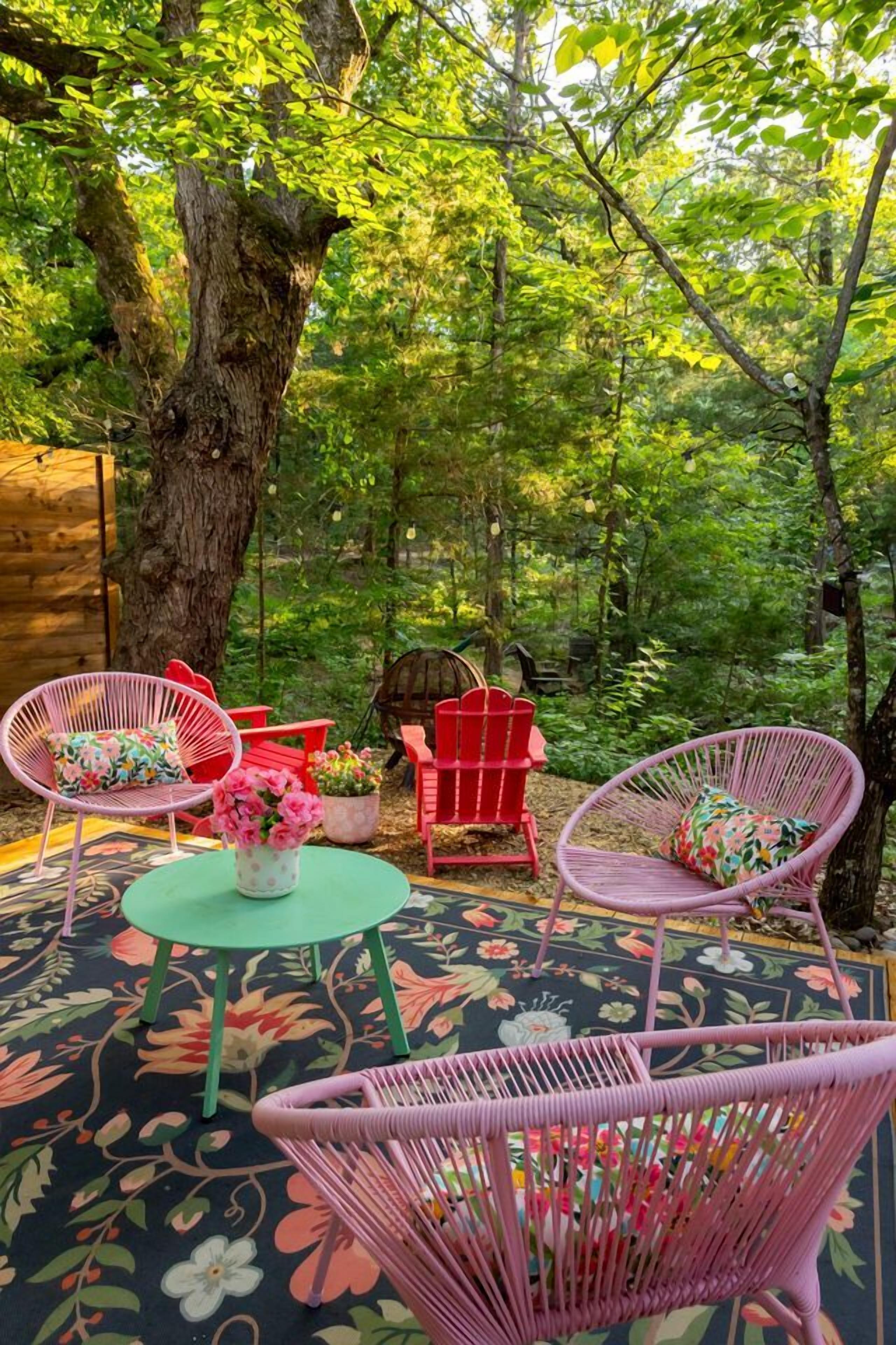 A forested outdoor area with wicker chairs, a small table, and a potted plant.