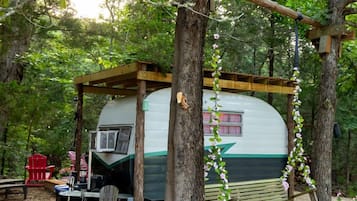 Une cabane de camping dotée d’un porche abrité, d’une balançoire et d’une table avec des chaises.