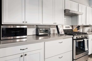 A modern kitchen with white cabinetry, a microwave, a toaster, and a gas stove.