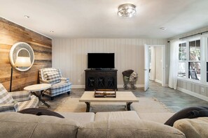 A living room with a sofa, armchair, TV, and a fireplace.