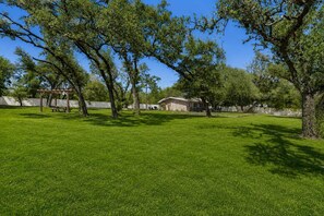 A grassy outdoor area with a picnic table and a covered seating area.
