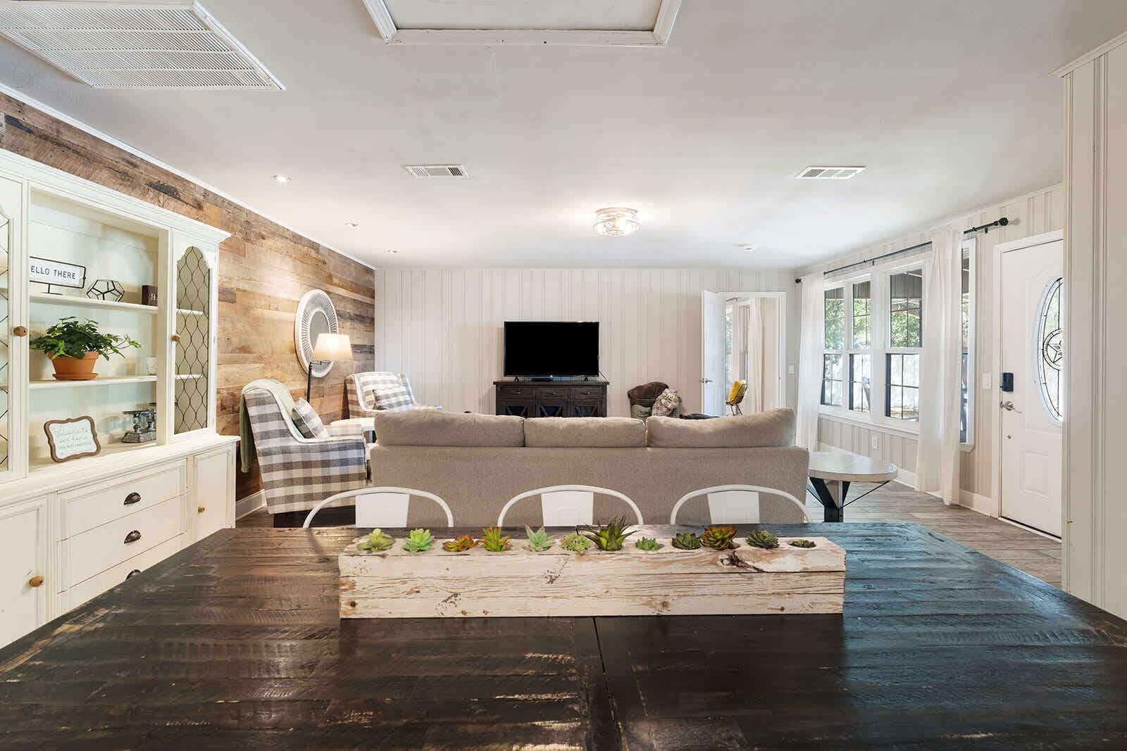 A living room with a sofa, chairs, a coffee table with plants, a TV, and a fireplace.
