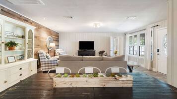 A living room with a sofa, chairs, a coffee table with plants, a TV, and a fireplace.