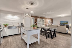 A modern kitchen with white cabinetry, a central island, and a dining area with a bench.
