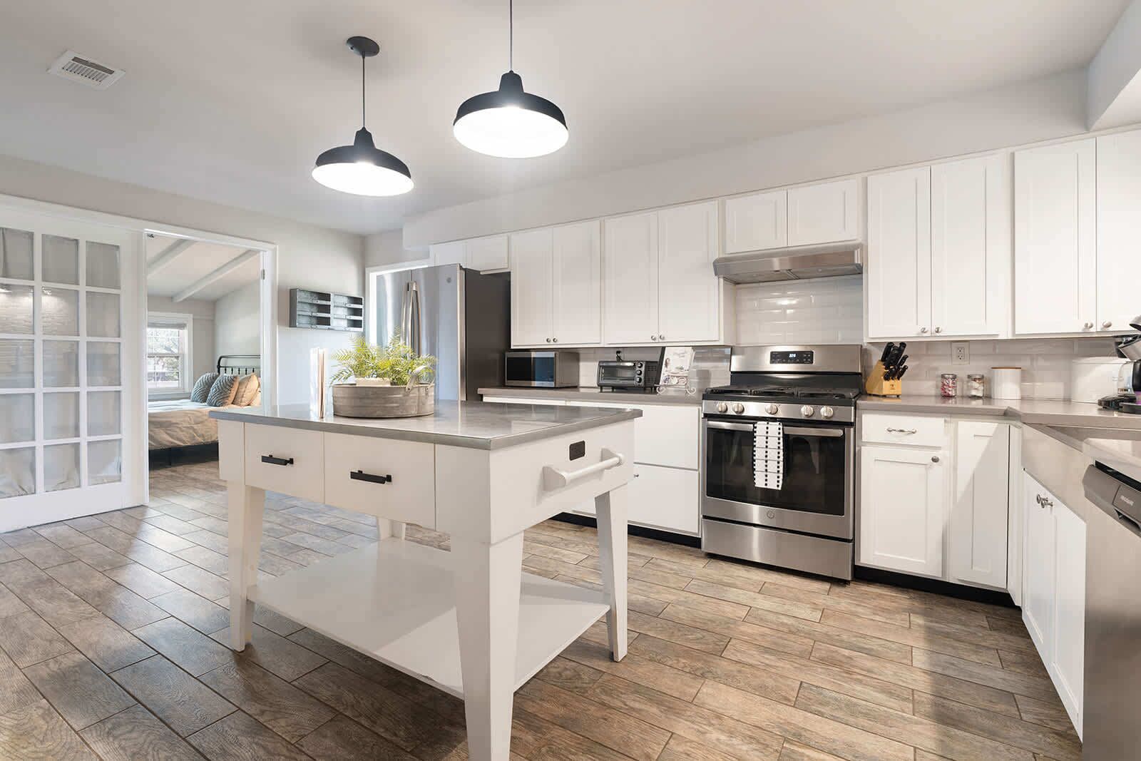 A modern kitchen with white cabinets, stainless steel appliances, and a central island with a sink.