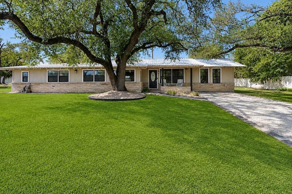 A single-story house with a front porch, a tree in the yard, and a well-maintained lawn.