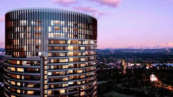 A modern high-rise building with a cylindrical glass facade and multiple balconies.