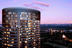 A modern high-rise building with a cylindrical glass facade and multiple balconies. - Cozy apartment Sydney Olympic Park free parking 03 (Sydney Olympic Park)