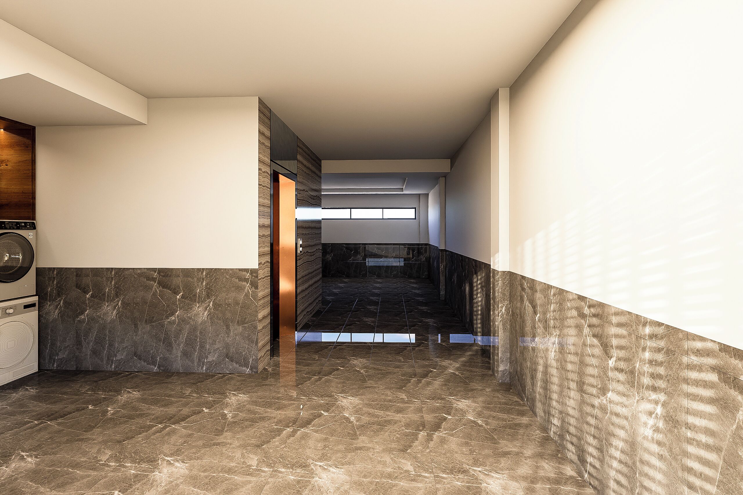 A modern interior with a marble floor, a washing machine, and a view through a doorway.