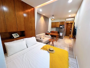 A hotel room with a bed, a sofa, a dining table, and a kitchen area. - La Doma Hotel-Airport Serviced Residence (Tan Son Hoa)