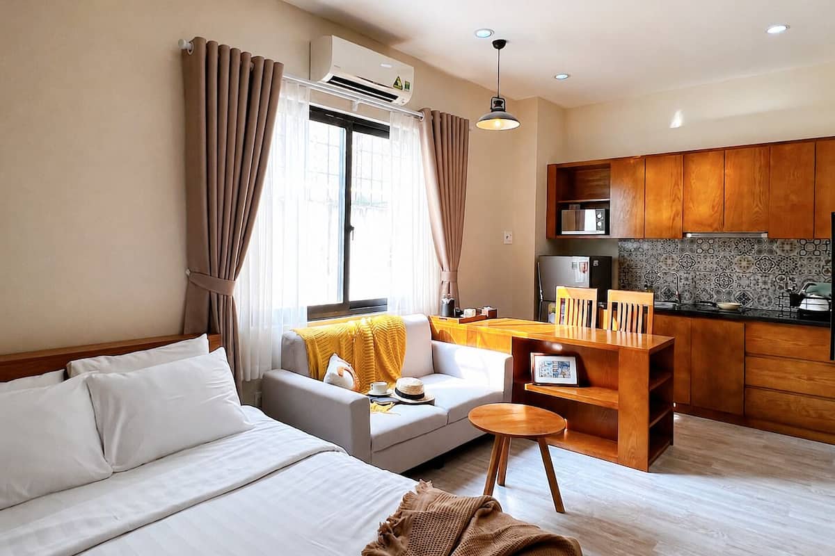 Ein modernes Hotelzimmer mit Bett, einer Sitzecke, einem kleinen Esstisch und einer Küchenzeile.