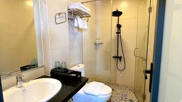 A bathroom with a sink, toilet, shower, and patterned floor tiles.
