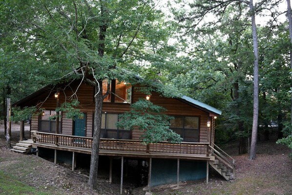 A log cabin with a deck, large windows, and a staircase leading to the entrance. - Fully Furnished Cabin with Fire Pit Perfect for Small Groups in Oklahoma (Broken Bow)